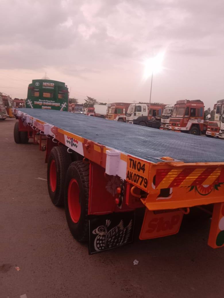 Empty 40 ft flatbed trailer in a truck park at dusk