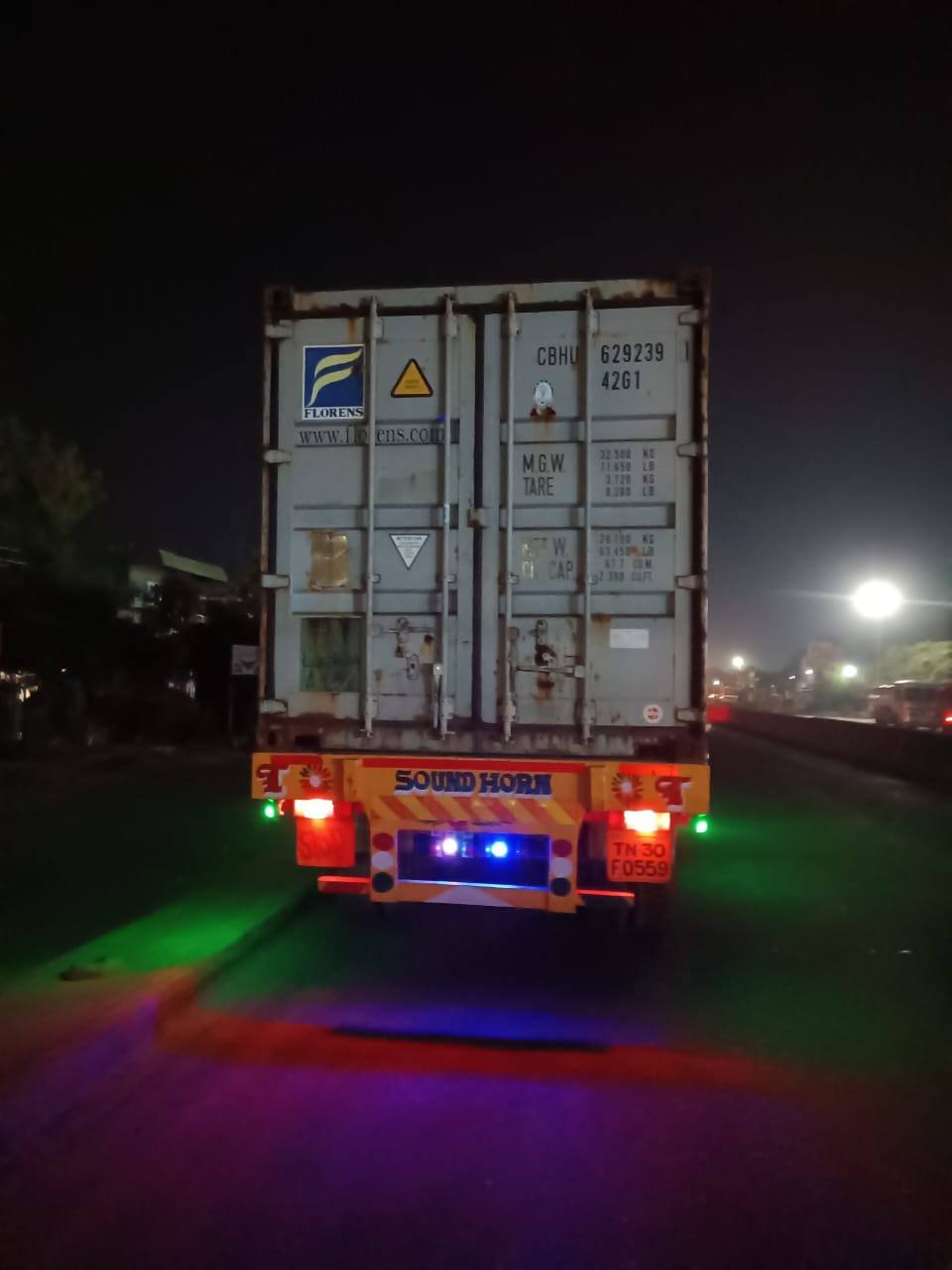 Forty-foot shipping container on a skeletal trailer, lit at night