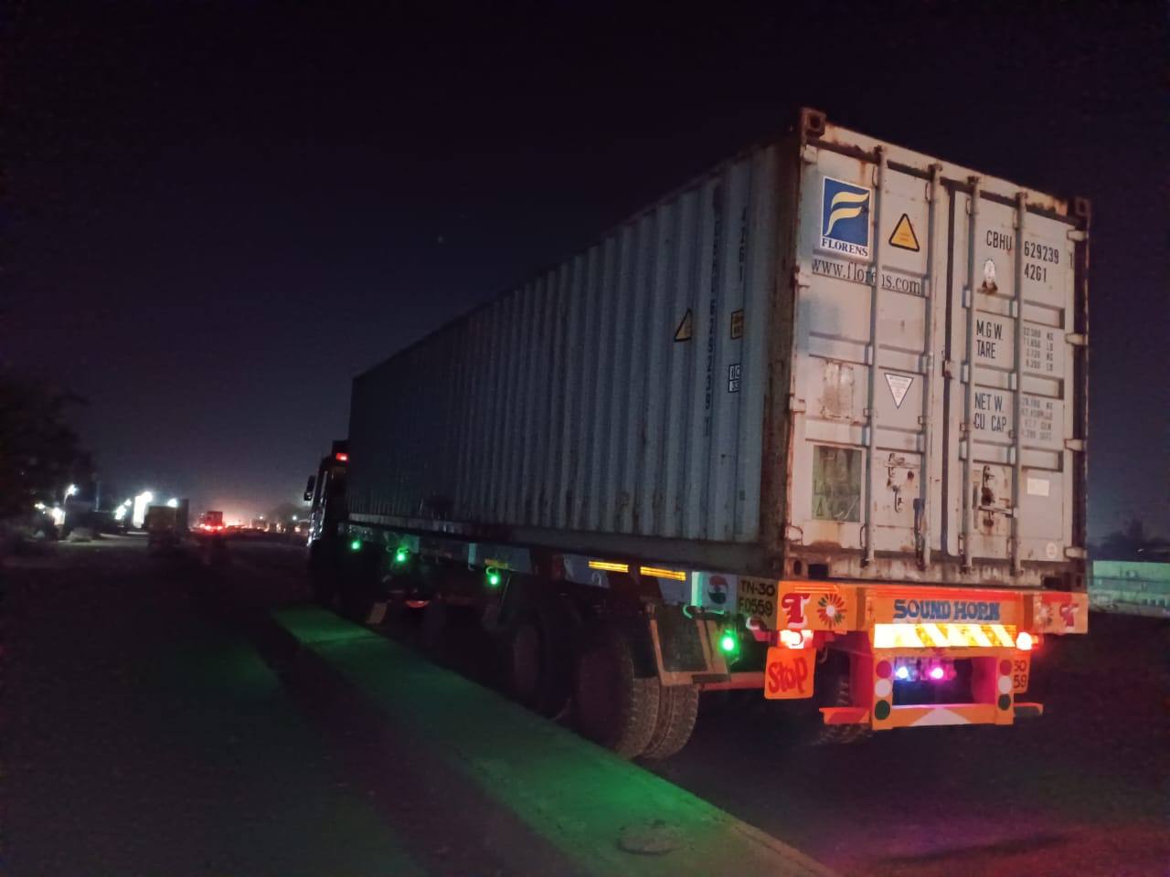 Forty-foot shipping container on a skeletal trailer on a road at night