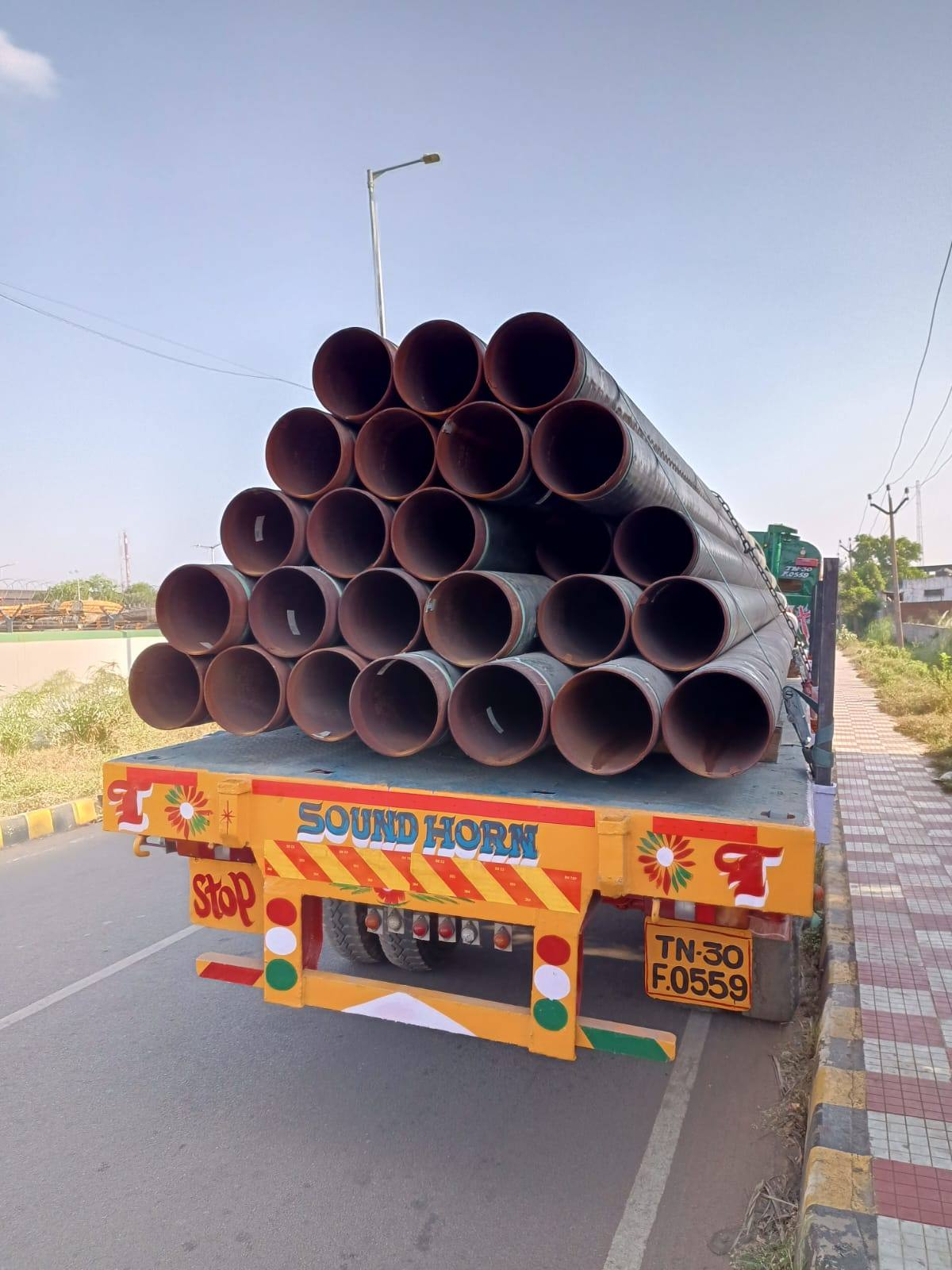 Large-diameter steel pipes stacked and chained on an MMM trailer