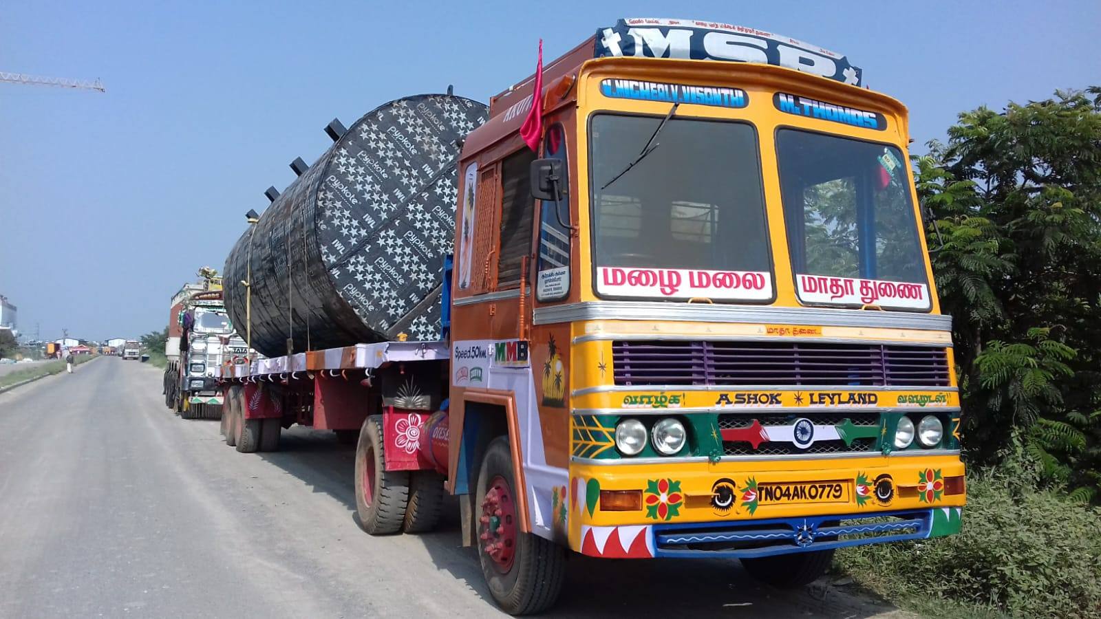 MMM tractor unit hauling a large wrapped cylindrical vessel on a highway
