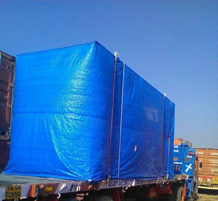 Cargo fully sheeted in blue tarpaulin and lashed down on an MMM flatbed trailer